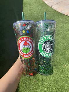 two starbucks cups with glitter on them are being held up by someone's hand