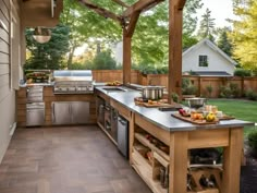 an outdoor kitchen with stainless steel appliances and grilling area in the middle of it