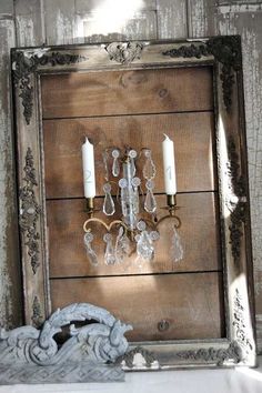 an old wooden frame with two candle holders and some glass beads hanging on the wall