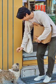 a man standing next to a dog on the side of a building holding a box