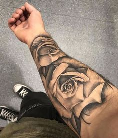 a man's arm with a black and white rose tattoo on the left forearm