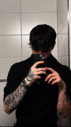 a man taking a selfie in front of a mirror with his arm tattoo on