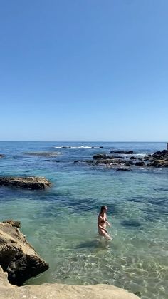 a person wading in the water near rocks