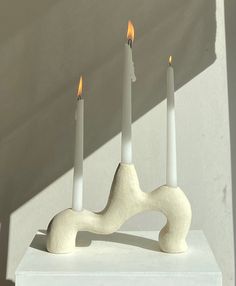 three candles sitting on top of a white block