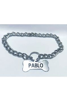 a dog tag on a chain with the word pablo written in black ink