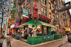 a street corner with an old building and many signs on the side of it in new york city