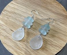 three sea glass dangles on a wooden surface