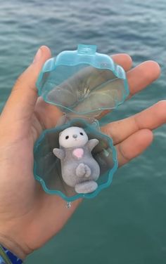 a hand holding a small plastic animal in it's palm next to the water