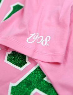 a pink shirt with white lettering on the front and green letters on the back that say'80s