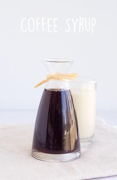 coffee syrup in a glass next to a bottle of milk on a white tablecloth