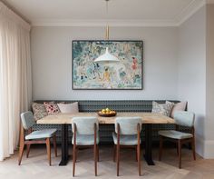 a dining room table with four chairs and a painting on the wall in the background