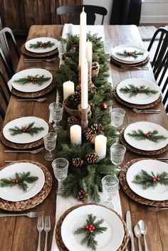 the table is set for christmas dinner with pine cones and candles