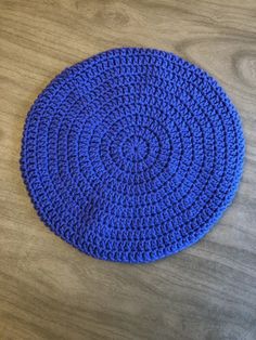 a blue crocheted placemat sitting on top of a wooden table