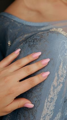 a woman's hand with pink manicures on her nails holding onto a blue dress