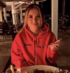 a woman sitting at a table with a plate of food in front of her