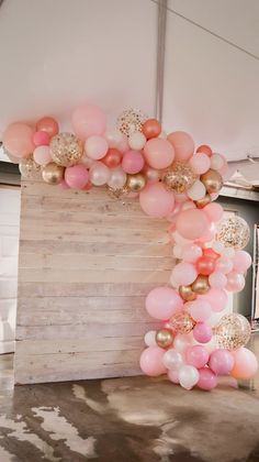 an arch made out of balloons and pink, gold and white balloons is on the floor