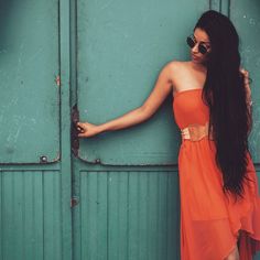 a woman in an orange dress leaning against a green door