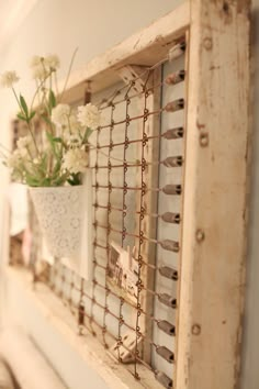 a vase with flowers is hanging on the wall next to an old window sill