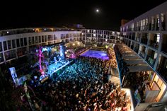 an aerial view of a crowd gathered in the city at night, with lights on