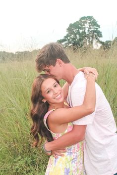 a young man and woman embracing in tall grass