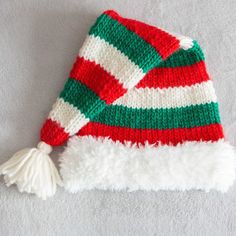 a red, white and green knitted hat with pom - pom on top