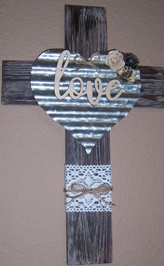 a wooden cross with the word love painted on it and some flowers hanging from it