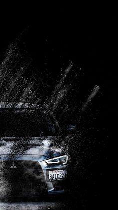 the front end of a car with water splashing on it