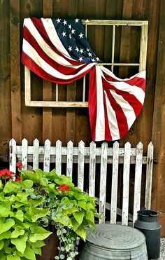 an american flag hanging on the side of a wooden building next to potted plants