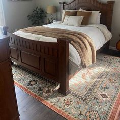 a bedroom with a large bed and wooden headboard on top of a carpeted floor