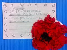 a piece of paper with writing on it and a red flower in front of it