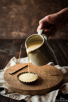 a person pouring coffee into a cup on top of a wooden board