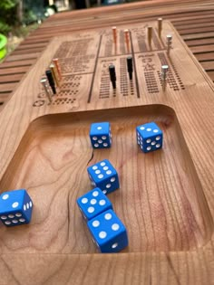 several blue dices sitting on top of a wooden board with holes in the middle