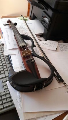 a violin sitting on top of a desk next to a keyboard