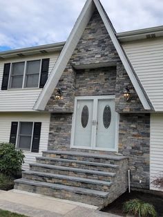 a house with stone steps leading up to the front door and side entrance that has two windows