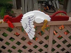 a wooden fence with roosters painted on the top and bottom, sitting in front of a house