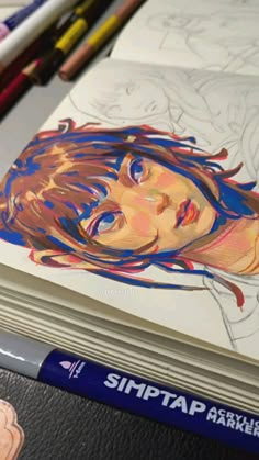 an image of a woman's face on a book with colored pencils next to it