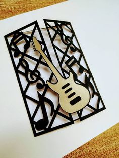 a guitar cut out on top of a piece of paper with music notes and trelliss