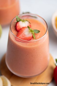 a strawberry smoothie in a glass with strawberries on top