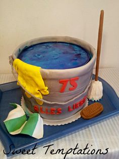 a birthday cake made to look like a bucket of blue liquid with a broom on top