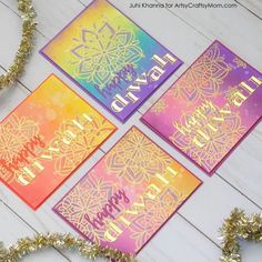 four cards with the words happy diwal written in gold and purple on them next to some tinsel