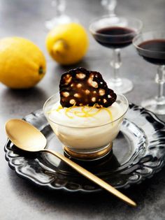 a dessert dish on a plate with two glasses of wine and lemons in the background