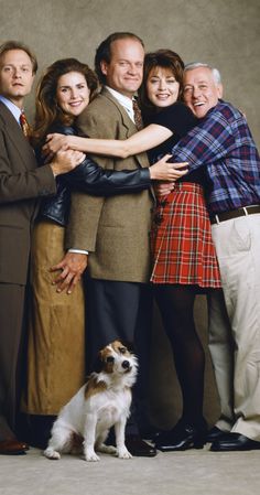 a group of people standing next to each other with a dog in front of them