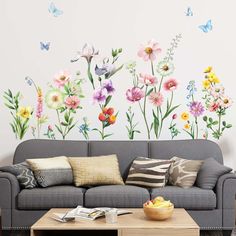 a living room with a couch, coffee table and flowers painted on the wall