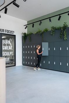 a woman standing in front of a locker with plants on it