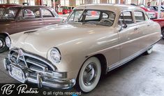 an old car is parked in a showroom next to other classic cars on display