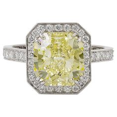 a fancy yellow diamond ring set in white gold with diamonds around the band and shoulders