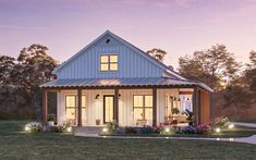 a small house is lit up with lights in the front yard and landscaping around it