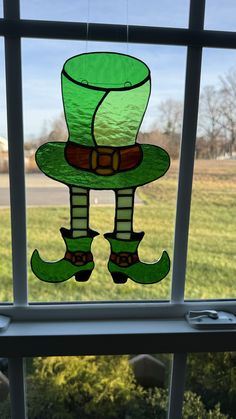 a stained glass window with a green hat and boots hanging from it's side