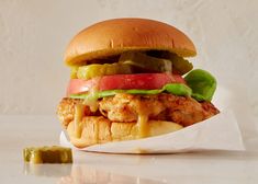 a chicken sandwich with lettuce, tomato and pickles