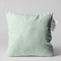 a light green pillow with a tag on it